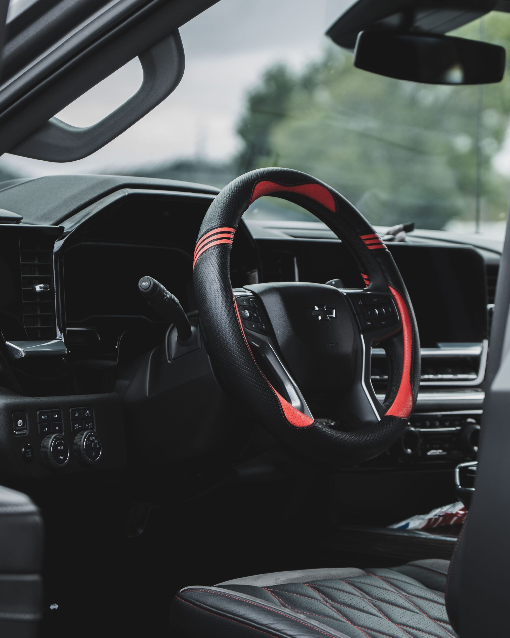Black and red sports steering wheel cover in a modern car interior