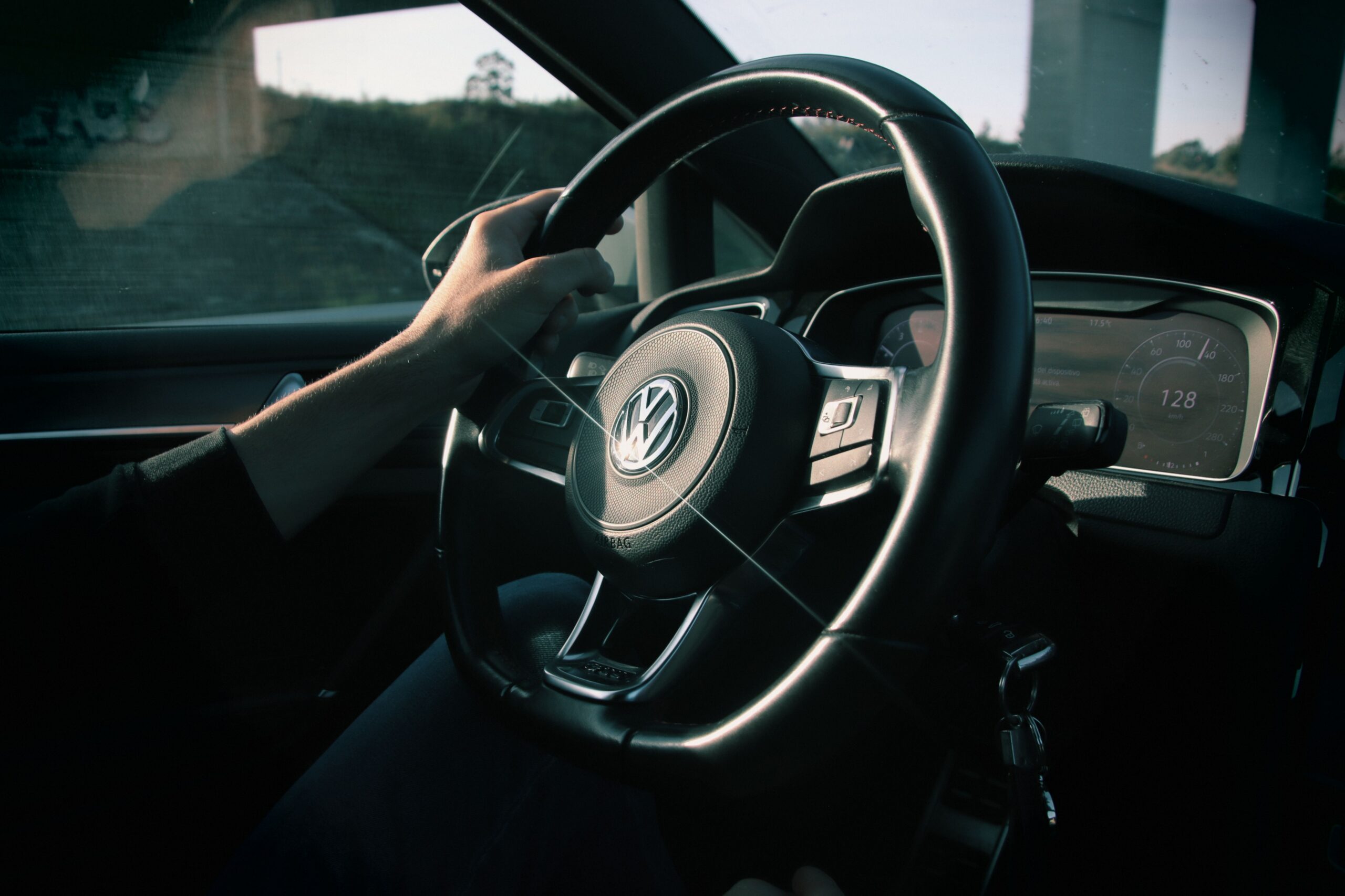 Driver holding a black leather steering wheel inside a car